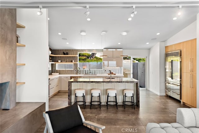 kitchen featuring a kitchen bar, built in refrigerator, modern cabinets, light brown cabinets, and open shelves