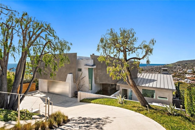 view of front of house with metal roof, stucco siding, driveway, and a standing seam roof