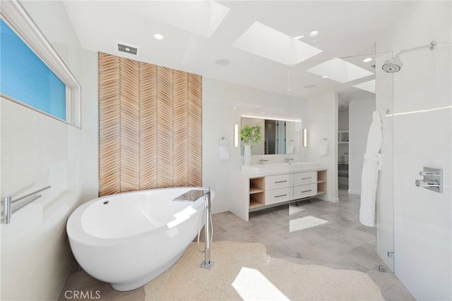 full bath with vanity, visible vents, a skylight, a freestanding tub, and a closet