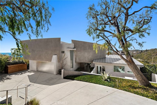 view of front of home featuring stucco siding, concrete driveway, a standing seam roof, and metal roof