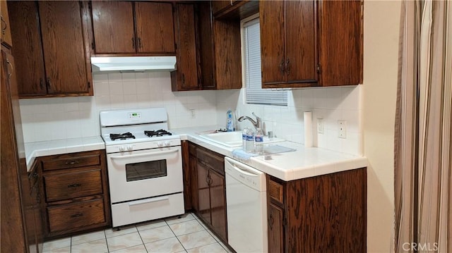 kitchen with white appliances, a sink, decorative backsplash, tile counters, and under cabinet range hood