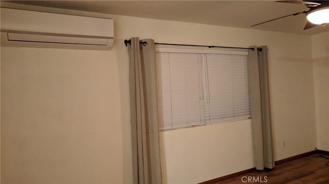 unfurnished bedroom with dark wood-style floors, ceiling fan, an AC wall unit, and baseboards