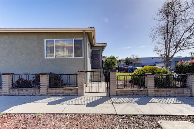 view of side of home with stucco siding and fence