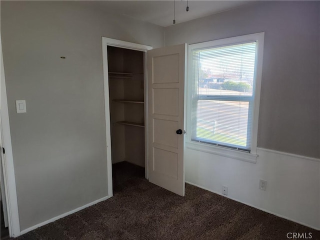 unfurnished bedroom with a closet and dark carpet