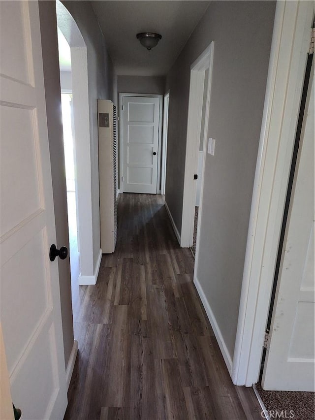 hall featuring baseboards, arched walkways, and dark wood finished floors