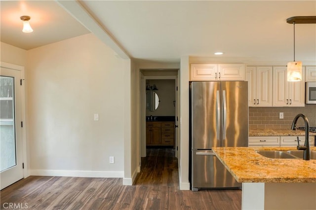 kitchen featuring light stone countertops, a sink, dark wood-type flooring, appliances with stainless steel finishes, and tasteful backsplash