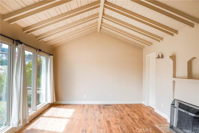 unfurnished living room featuring vaulted ceiling with beams, baseboards, and wood finished floors