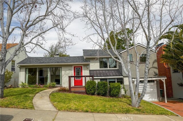 tri-level home featuring stucco siding, an attached garage, a front yard, and a shingled roof