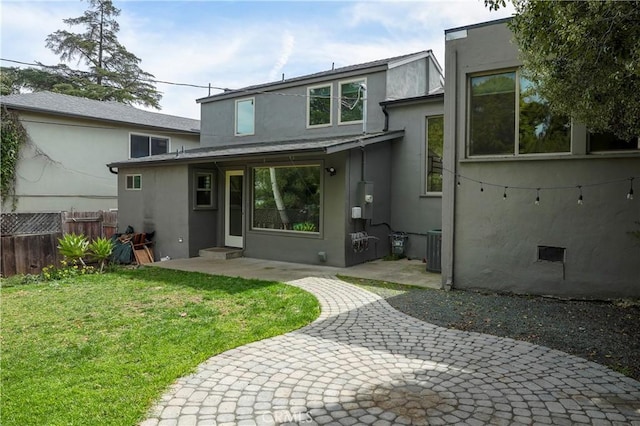 rear view of property featuring stucco siding, a patio, fence, a yard, and crawl space