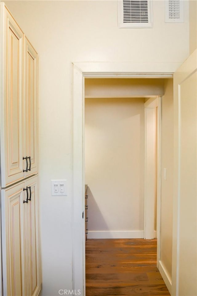 corridor featuring wood finished floors, visible vents, and baseboards