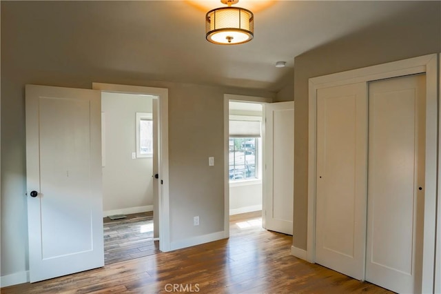 unfurnished bedroom featuring a closet, baseboards, and wood finished floors