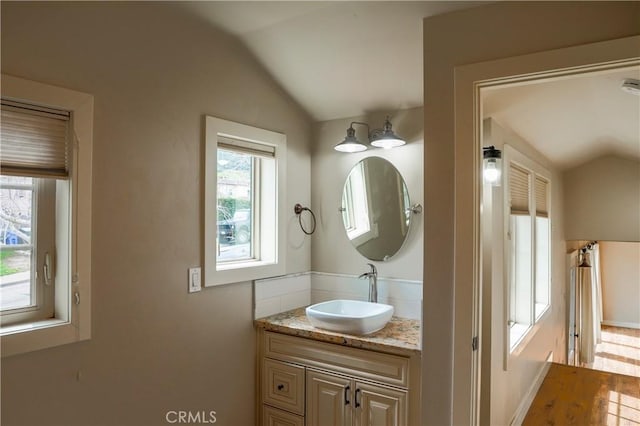 bathroom with vanity, lofted ceiling, and wood finished floors