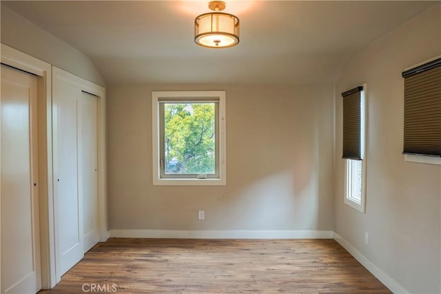 unfurnished bedroom featuring baseboards, lofted ceiling, and wood finished floors