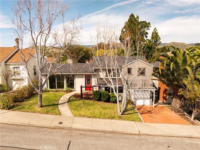 view of front of home featuring stucco siding, driveway, and a front lawn