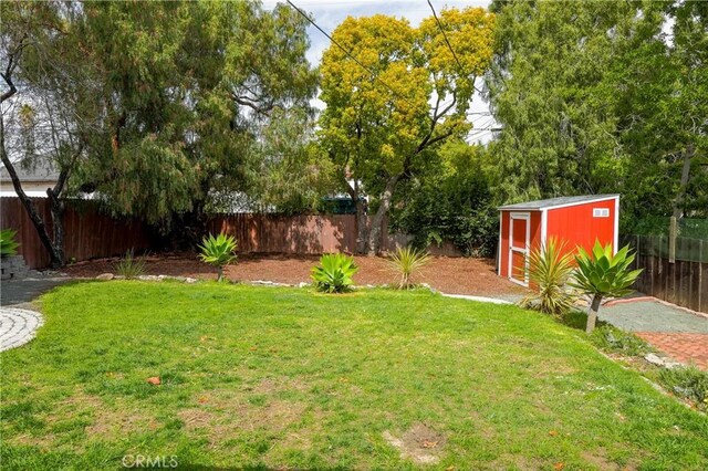 view of yard with an outbuilding, a storage unit, and a fenced backyard