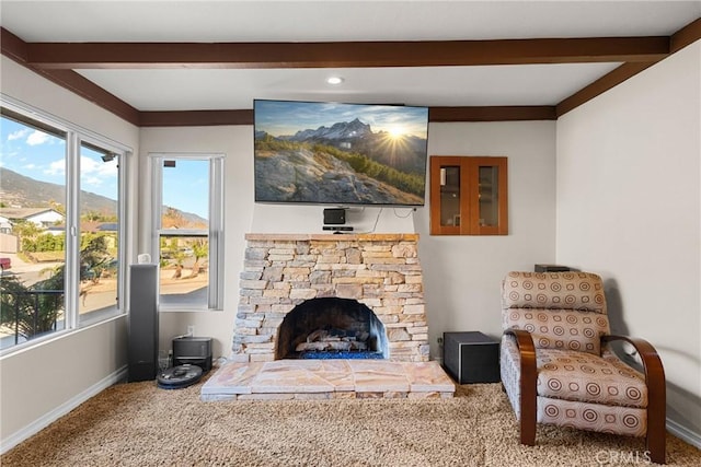 living room with beam ceiling, a stone fireplace, baseboards, and carpet floors