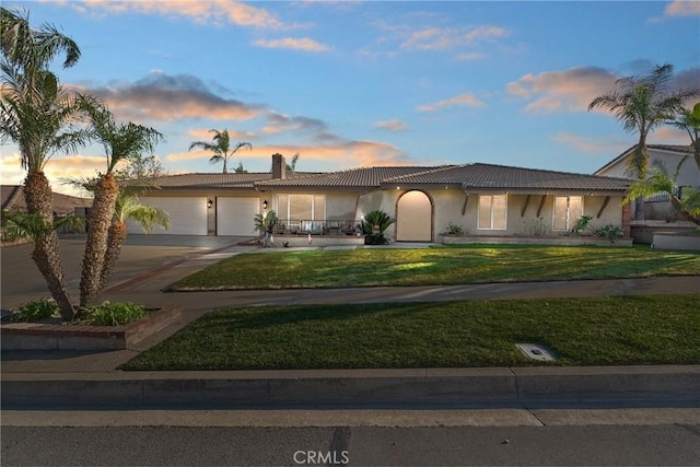 ranch-style house with a garage, concrete driveway, a front lawn, and a tiled roof