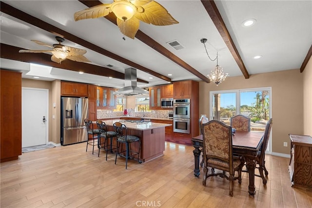 kitchen featuring brown cabinetry, island exhaust hood, visible vents, and appliances with stainless steel finishes