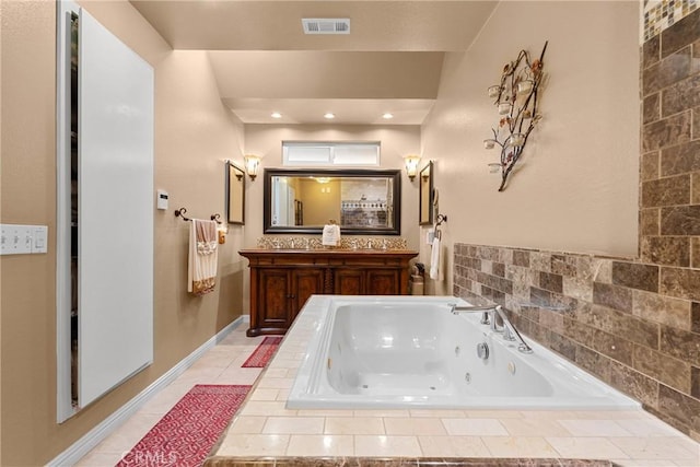 bathroom featuring vanity, a tub with jets, visible vents, baseboards, and tile patterned flooring