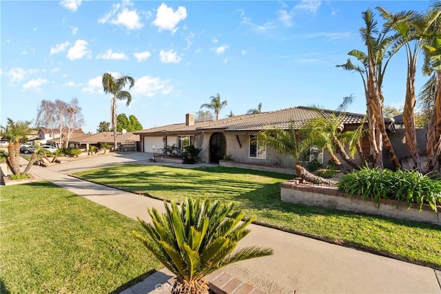 view of front of house featuring a front yard, stucco siding, a chimney, a garage, and driveway