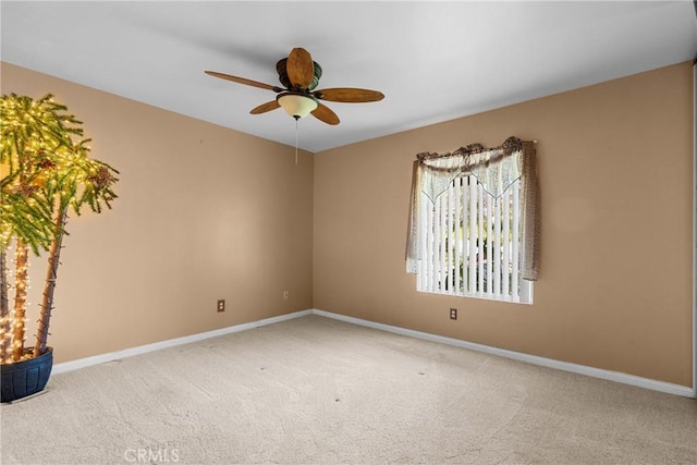 carpeted spare room featuring baseboards and a ceiling fan