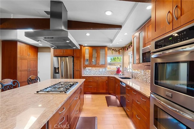 kitchen featuring brown cabinetry, appliances with stainless steel finishes, island range hood, and a sink