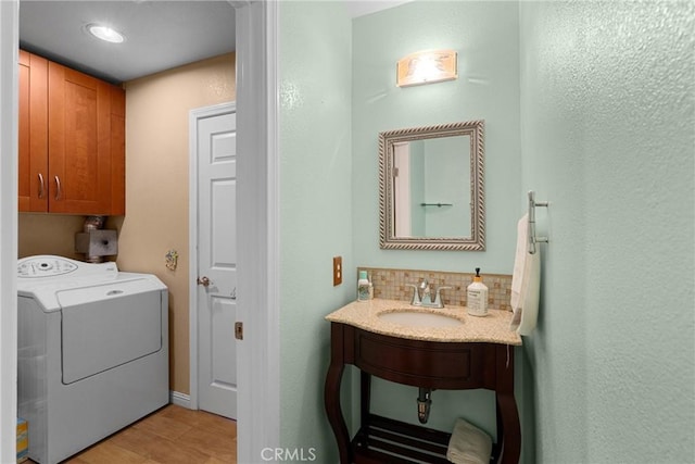 clothes washing area with washer / clothes dryer, cabinet space, and a sink