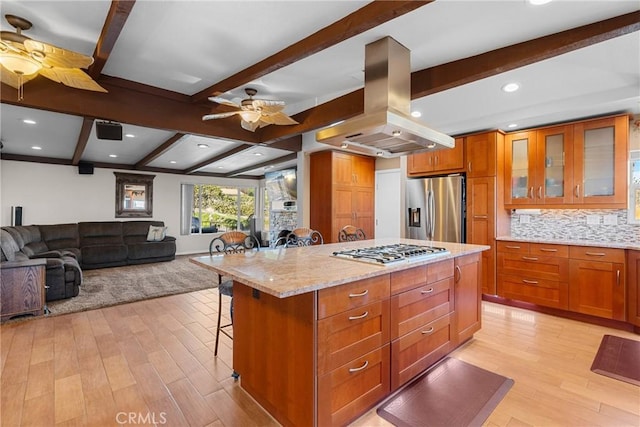 kitchen with a breakfast bar area, light wood-style flooring, ceiling fan, appliances with stainless steel finishes, and island range hood