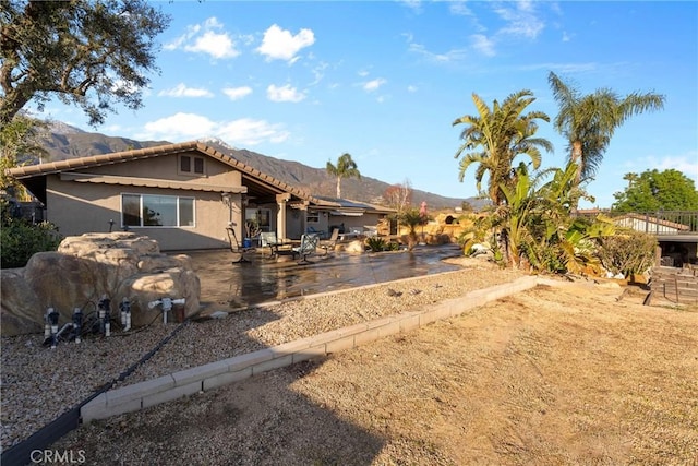 exterior space featuring a tiled roof, stucco siding, a mountain view, and a patio area