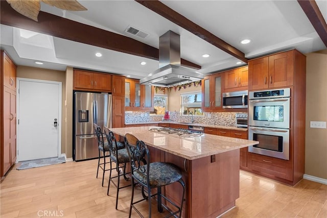 kitchen featuring visible vents, brown cabinets, appliances with stainless steel finishes, and island range hood