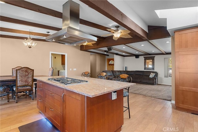 kitchen featuring light wood-type flooring, stainless steel gas stovetop, a center island, and island range hood