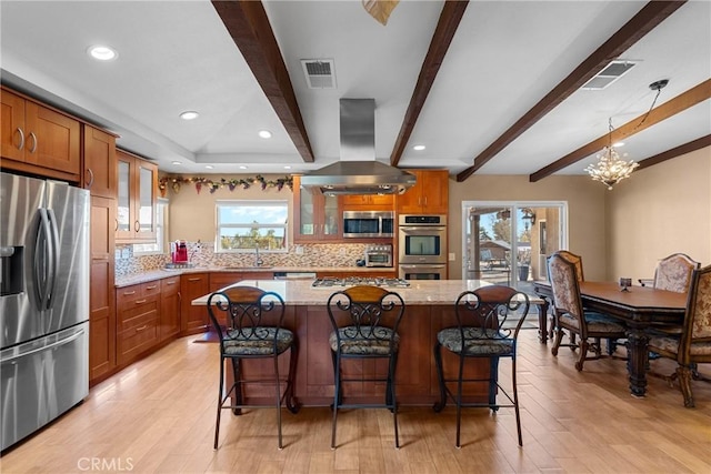 kitchen featuring island exhaust hood, brown cabinets, appliances with stainless steel finishes, and a sink