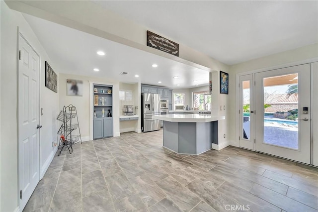 kitchen featuring stainless steel appliances, recessed lighting, light countertops, gray cabinetry, and a peninsula