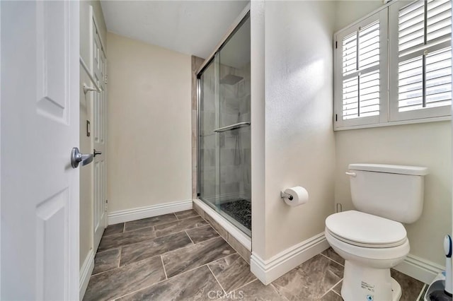 full bath with baseboards, a shower stall, and toilet