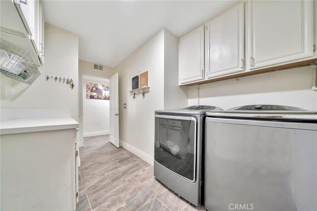 washroom featuring visible vents, independent washer and dryer, cabinet space, and baseboards