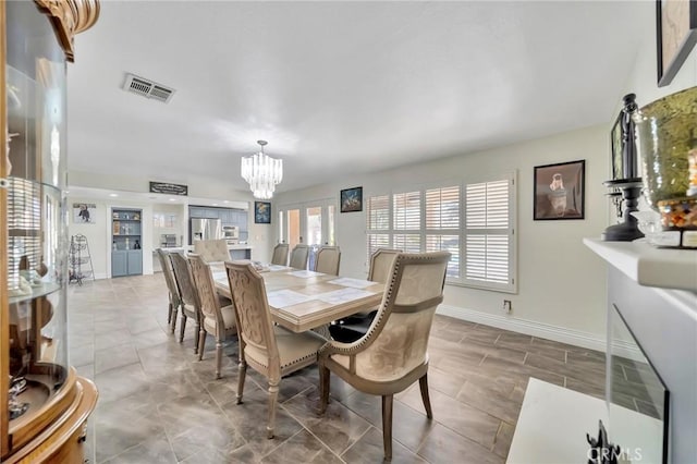 dining space with visible vents, a notable chandelier, and baseboards