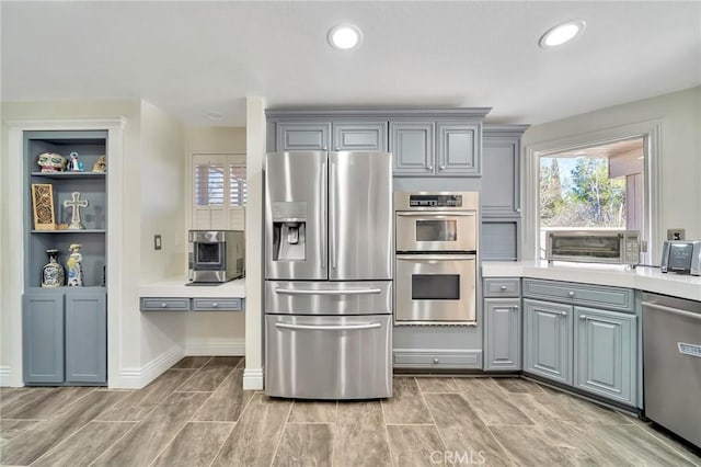 kitchen with appliances with stainless steel finishes, recessed lighting, light countertops, and gray cabinetry