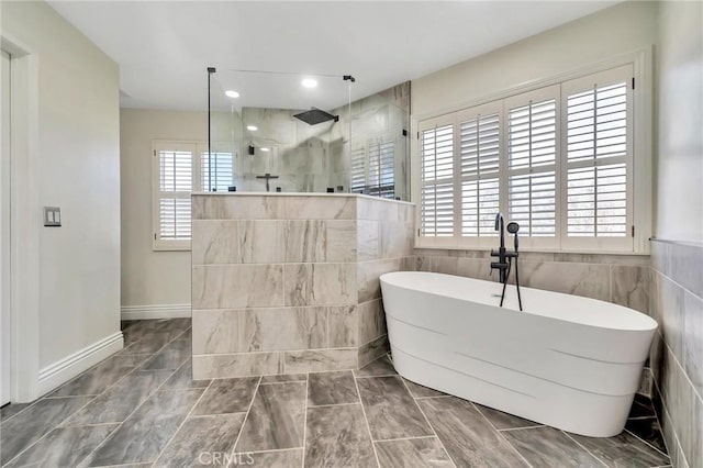 bathroom with recessed lighting, a freestanding tub, tile walls, and walk in shower