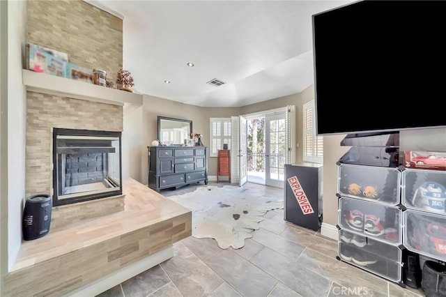 interior space with a tile fireplace, french doors, and visible vents