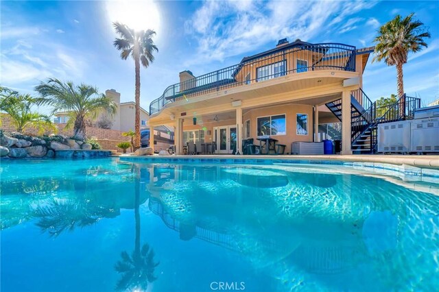 outdoor pool featuring a ceiling fan, french doors, a patio area, and stairway