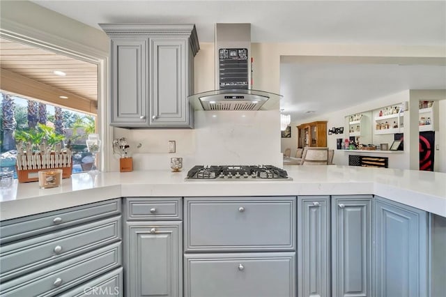 kitchen with gray cabinets, light countertops, stainless steel gas stovetop, and ventilation hood