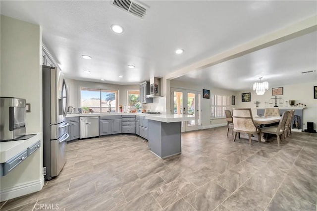 kitchen featuring stainless steel appliances, gray cabinets, light countertops, visible vents, and a peninsula