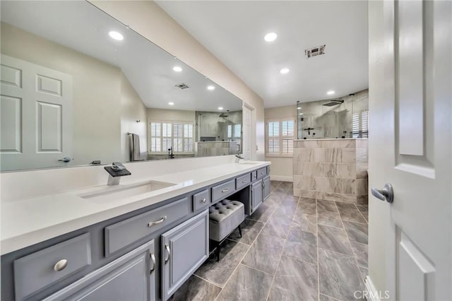 full bath featuring double vanity, a wealth of natural light, visible vents, and a sink