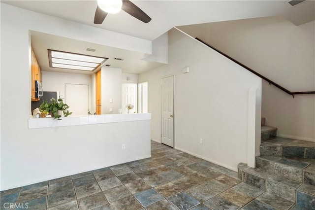 interior space featuring visible vents, a ceiling fan, stone finish flooring, baseboards, and stairs