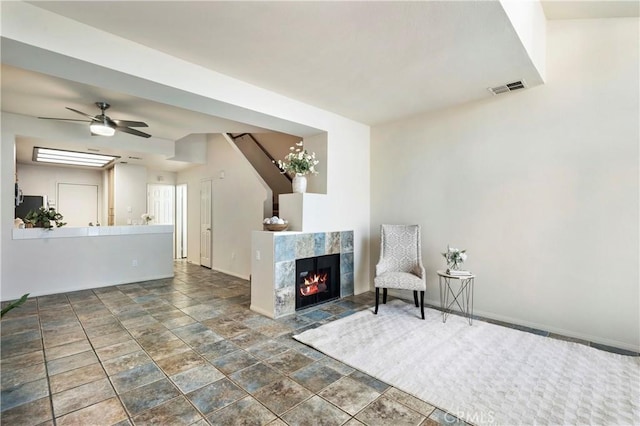 unfurnished room with a ceiling fan, visible vents, a fireplace, and baseboards