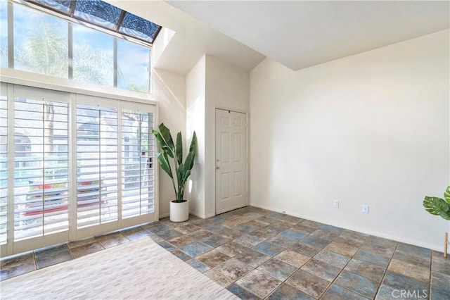 unfurnished room featuring a skylight and stone finish floor