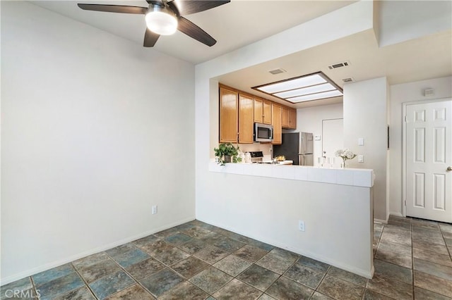 kitchen featuring light countertops, visible vents, appliances with stainless steel finishes, stone finish floor, and baseboards