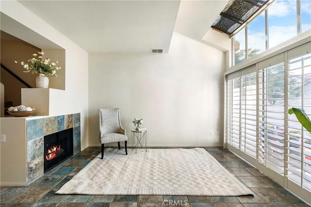 sitting room with a tile fireplace, visible vents, and baseboards