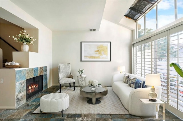 living room featuring a high ceiling, visible vents, and a tiled fireplace