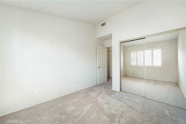 unfurnished bedroom with carpet floors, visible vents, and a closet